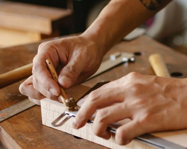 a person's hands working wood with a cutting tool